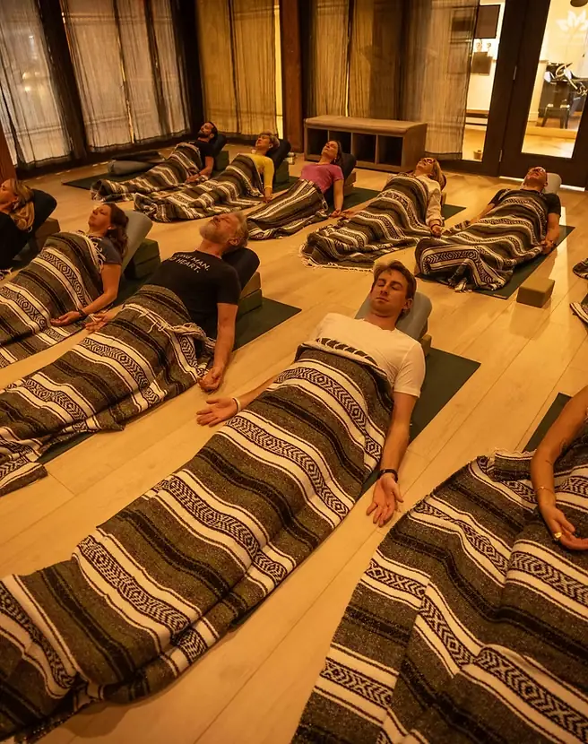 Students resting under striped blankets during a restorative class in the studio